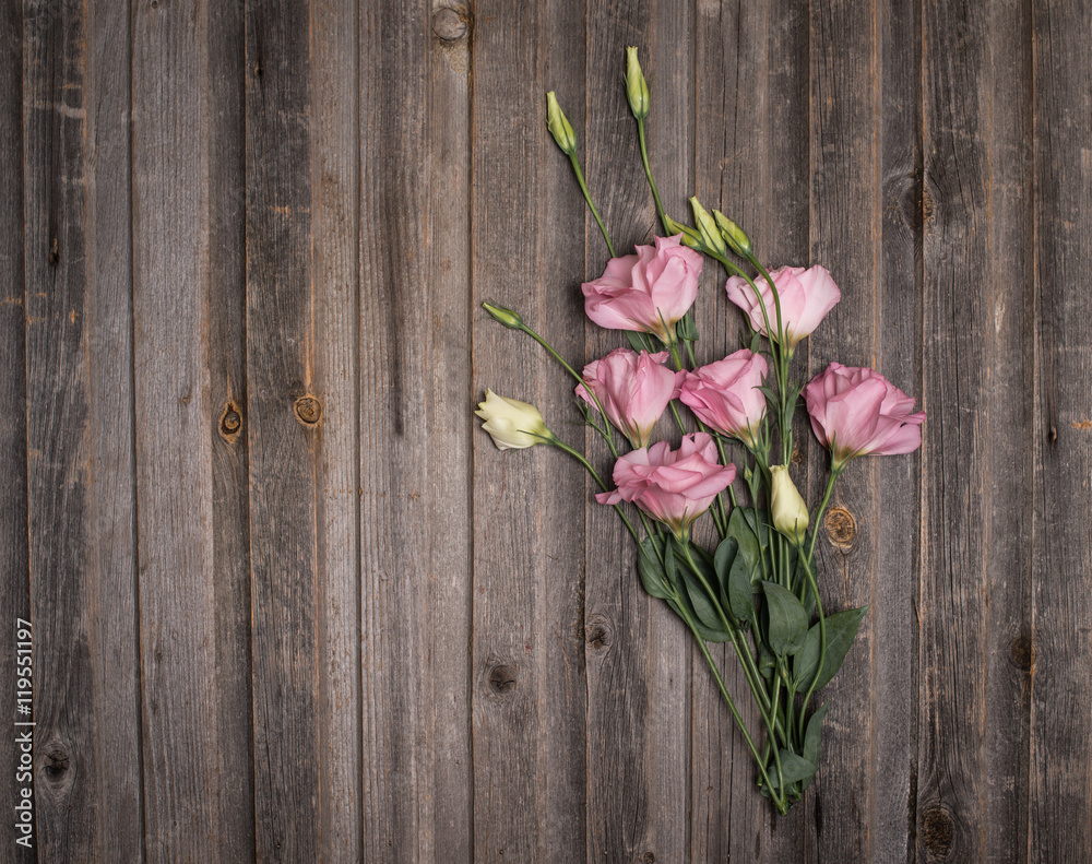 Pink eustoma flowers on weathered wooden background. Retro styled floral background. Pink eustoma flowers on weathered wooden background. Retro styled floral background.