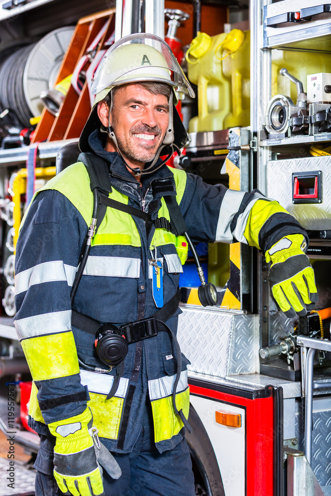 Naklejka premium Feuerwehrmann in Uniform lehnt am Einsatzfahrzeug der Feuerwehr