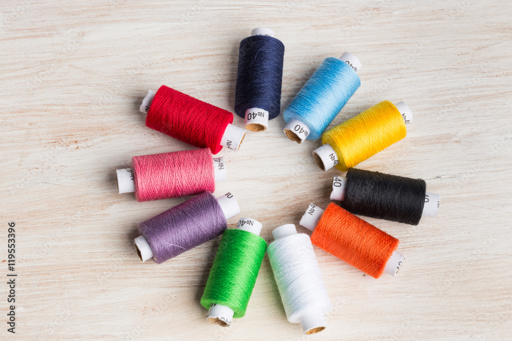 Bobbins threads multicolored. Old sewing tools on the wooden background. Bobbins threads multicolored. Old sewing tools on the wooden background.