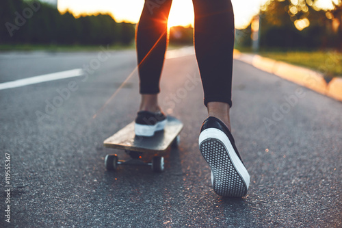 Canvas Print young skateboarder legs riding on skateboard in front of the sun