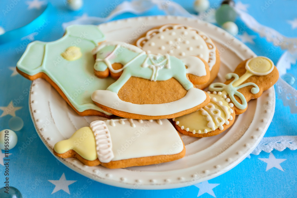 Baby glazed cookies in plate on decorated table Baby glazed cookies in plate on decorated table