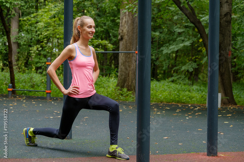 Young slim woman doing workout on training ground in a park