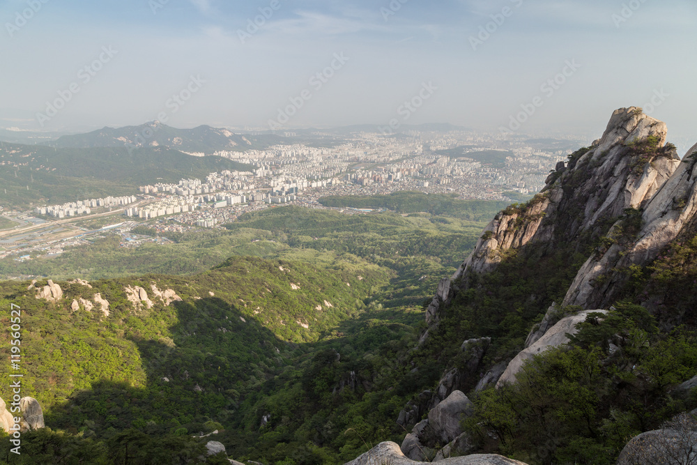 View of the city far away from above and steep granite peaks of Jaunbong Peak on Dobongsan Mountain at the Bukhansan National Park in Seoul, South Korea.