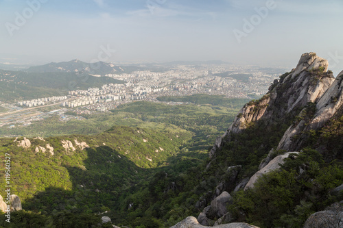 View of the city far away from above and steep granite peaks of Jaunbong Peak on Dobongsan Mountain at the Bukhansan National Park in Seoul, South Korea.