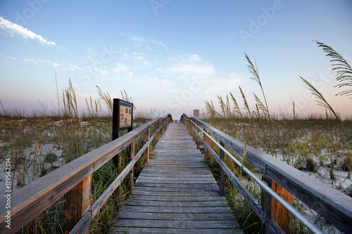 Wooden boardwalk at beach against sky