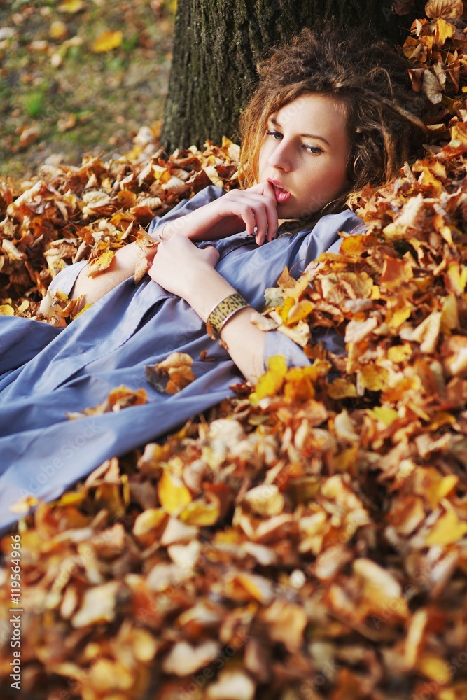 Cute teen girl in a light purple cloak with sad eyes lies on a p