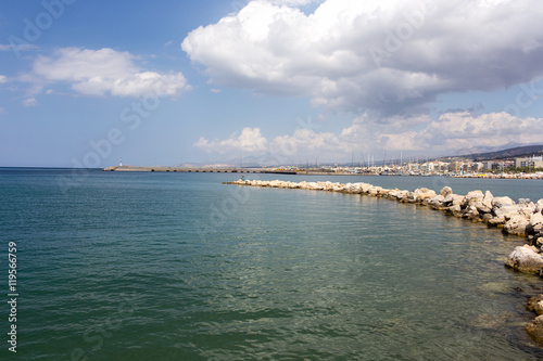 Stone pier stretching into the sea on the background of the old