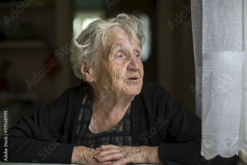 Elderly woman looks out the window.
