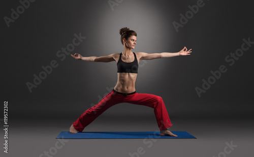 Woman practicing yoga in studio, on gray backdrop
