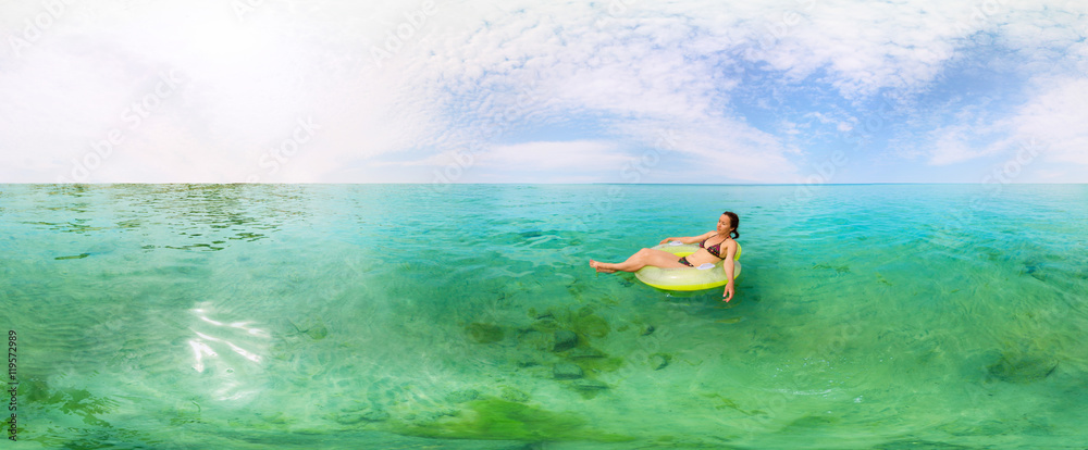 Girl in inflatable ring floating in the azure sea