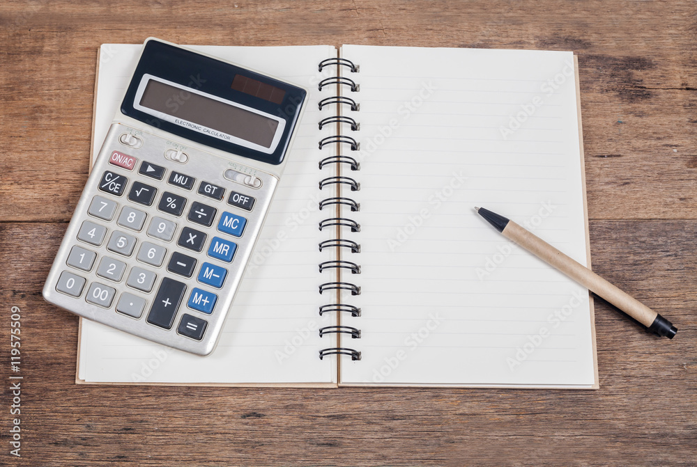 notebook showing empty page  and calculator on wooden