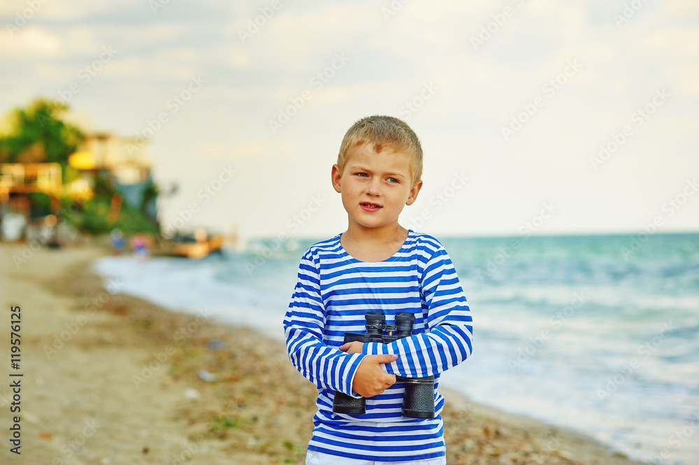 The little boy in the vest with the binoculars , walks on the beach The little boy in the vest with the binoculars , walks on the beach