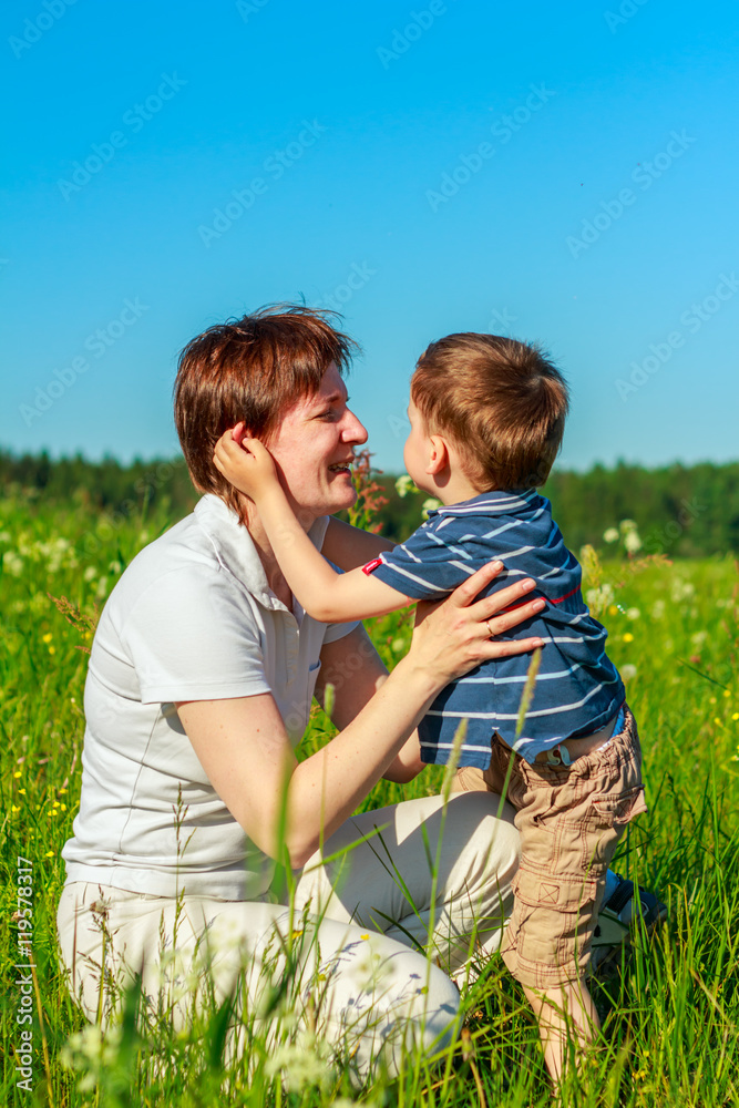 Fototapeta premium Young brunette with short hair playing with his son in the field