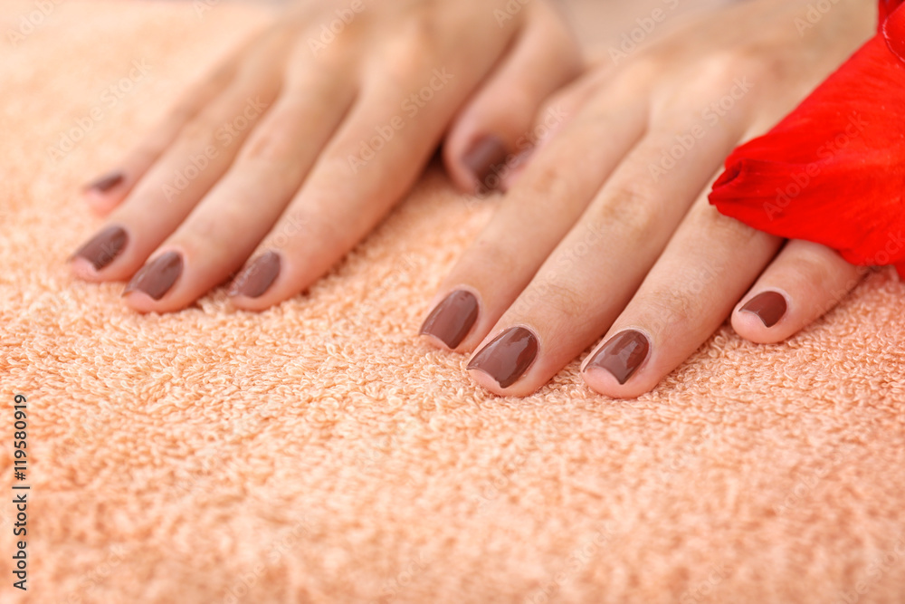 Female hands with brown manicure on towel in spa salon, closeup