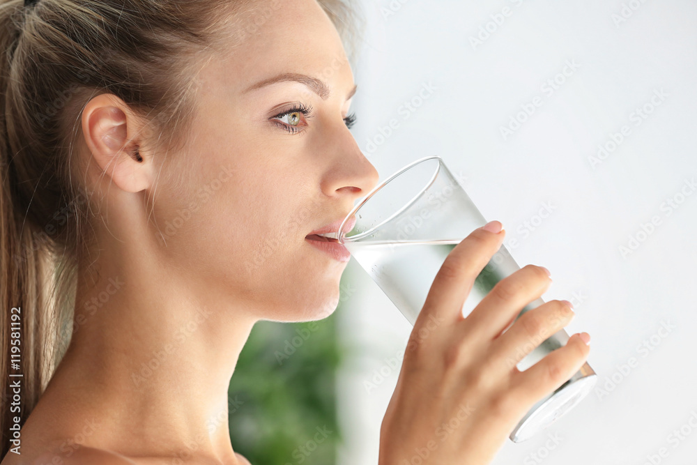 Beautiful girl drinking water on light background Beautiful girl drinking water on light background