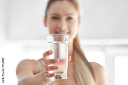 Tablou canvas Beautiful girl drinking water on light background