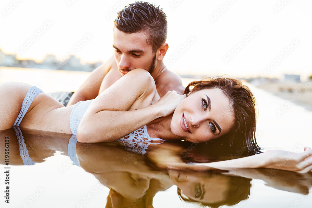 happy young couple having fun, man and woman in the sea on the beach. vintage retro style with soft focus and sun flare happy young couple having fun, man and woman in the sea on the beach. vintage retro style with soft focus and sun flare