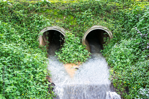 Water flowing from  drain pipe into a river photo