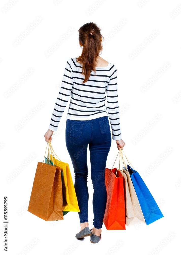 back view of going woman with shopping bags . beautiful girl in motion. Girl in a striped sweater went off shopping.