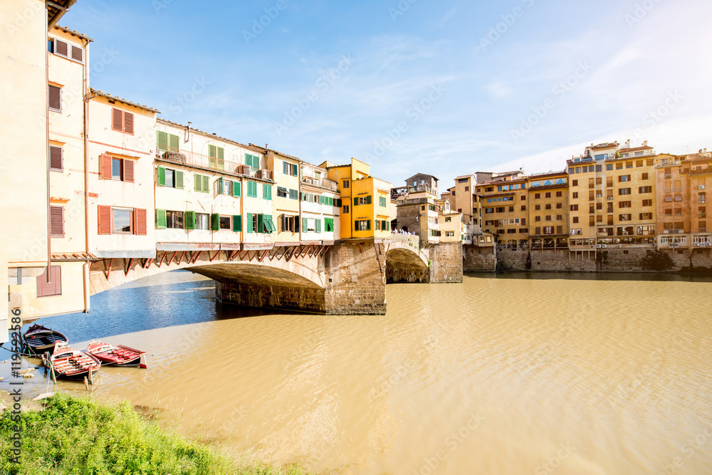 Obraz premium Cityscape view on famous Ponte Vecchio bridge with boats on the river in Florence
