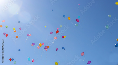 Balloons. The children released a lot of balls with ropes in the sky. Balloons in the blue sky in the rays of the sun.