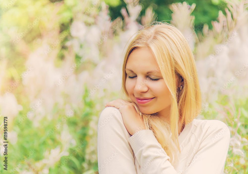 Young, charming, beautiful woman in gentle, warm atmosphere feels the touch of an angel on her shoulder. Outdoor portrait.