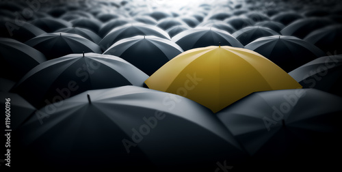 Yellow umbrella in the middle of a sea of black umbrellas, representing special element, a different view in the society.