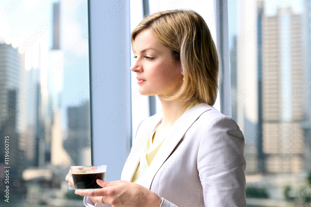 Portrait of business woman standing with coffee near window