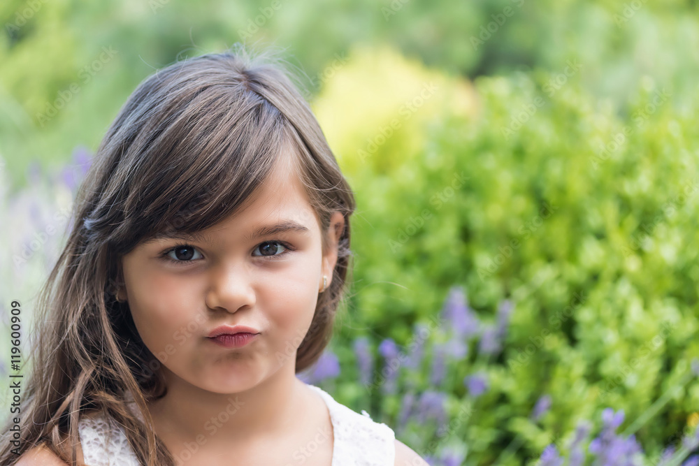 Portrait of attractive little girl outdoors. Little girl with pursed lips is looking at the camera Portrait of attractive little girl outdoors. Little girl with pursed lips is looking at the camera