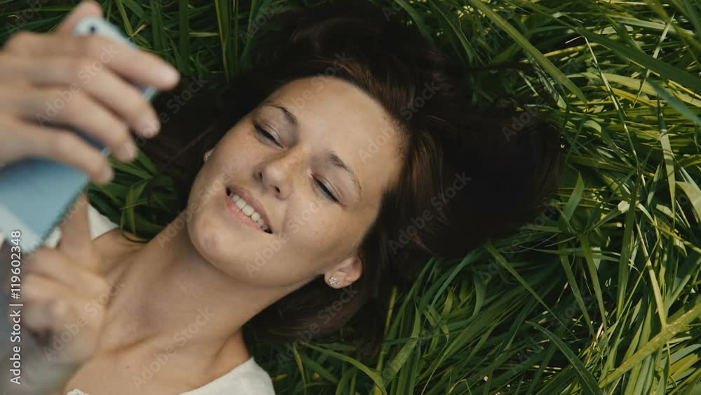 woman taking break lying on the grass and using your smartphone woman taking break lying on the grass and using your smartphone