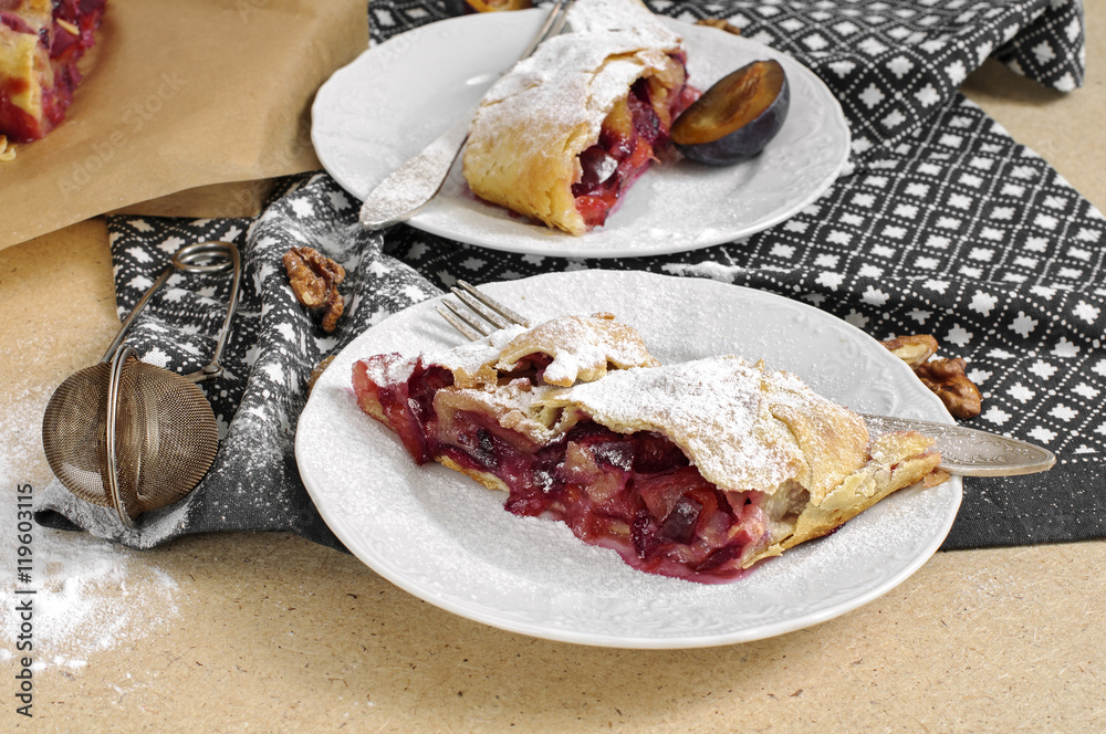 Slice of fresh baked homemade strudel with plum, walnuts and sug