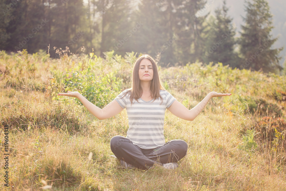 Beautiful girl meditating in the nature, at sunset Beautiful girl meditating in the nature, at sunset