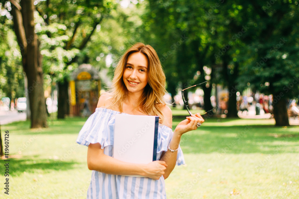 blond girl student walking on a green park in the white dress she smiles a lovely smile ,
holding her glasses to view and folder with documents
blond girl student walking on a green park in the white dress she smiles a lovely smile ,
holding her glasses to view and folder with documents