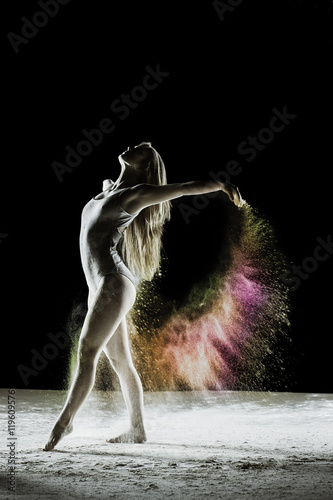Fototapeta Naklejka Na Ścianę i Meble -  Finale - Young dancer traces patterns through a cloud of powder as she dances against a dark background
