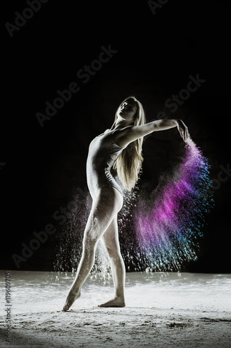 Fototapeta Naklejka Na Ścianę i Meble -  Wings - Young dancer traces patterns through a cloud of powder as she dances against a dark background