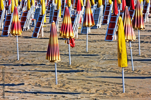 End of summer - Parasols and sun loungers closed on the beach photo