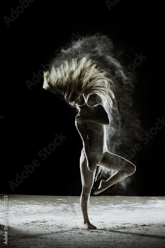 Fototapeta Naklejka Na Ścianę i Meble -  Fairy - Young dancer traces patterns through a cloud of powder as she dances against a dark background