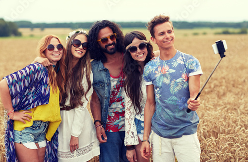 hippie friends with smartphone on selfie stick