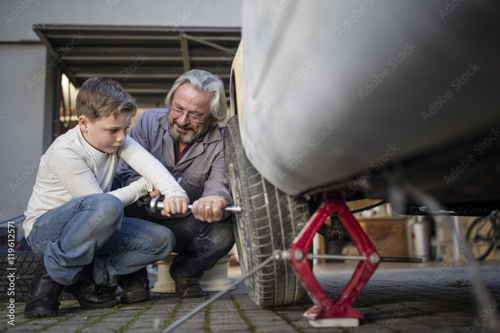 Senior man and boy changing car tire Senior man and boy changing car tire