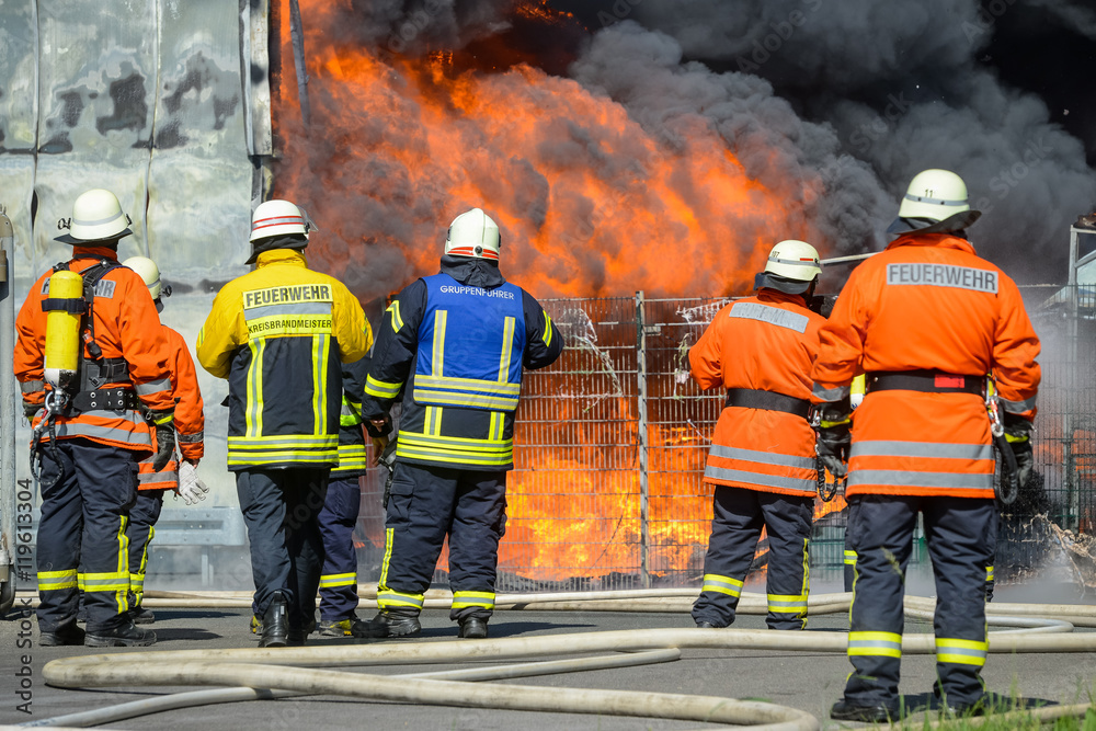 Fototapeta premium Feuerwehrmänner vor brennendem Gebäude
