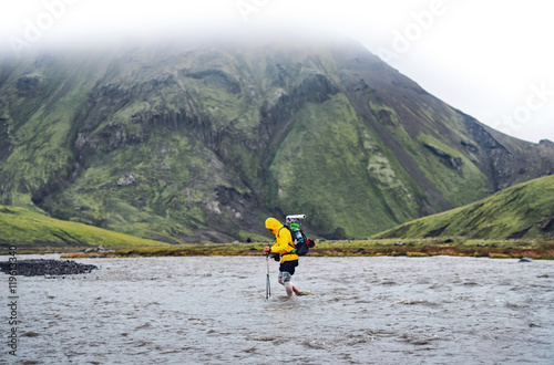 Tableau sur toile Hiker man with backpack crossing a river in  Iceland
