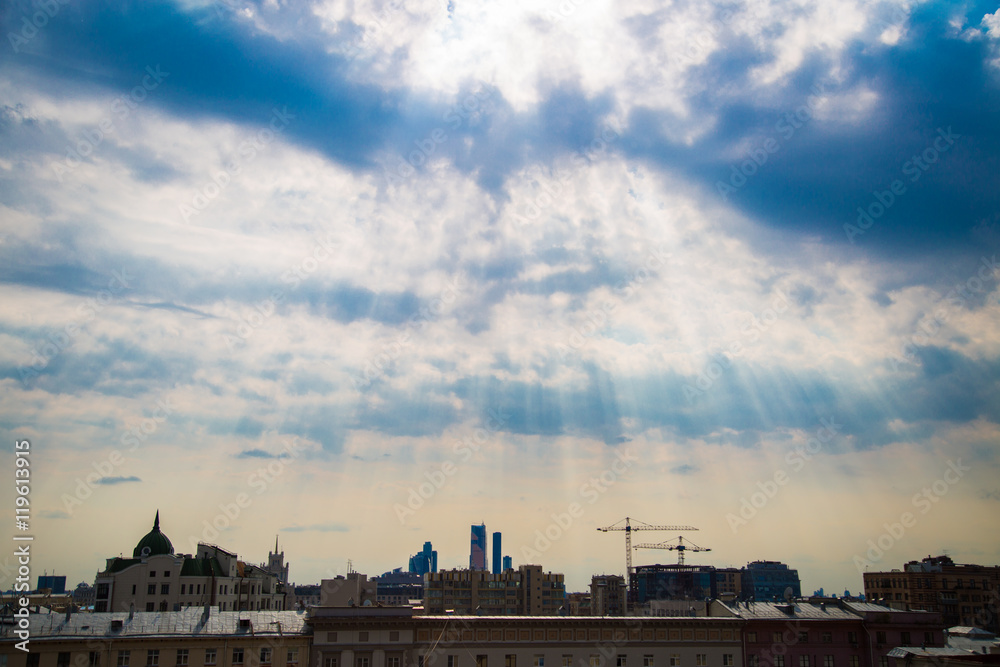 Sun rays through the clouds over the city rooftops