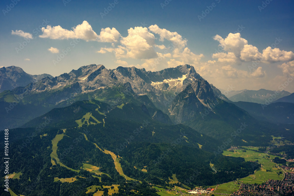 Beautiful view at highest mountain peak Zugspitze and Alpspix with Garmisch Partenkirchen from Wank mountain. Hot summer day and amazing cloudy sky. Bavaria, Germany.