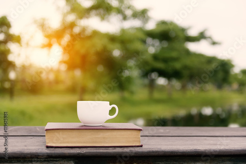 .Vintage old book with coffee cup on wood balcony by river