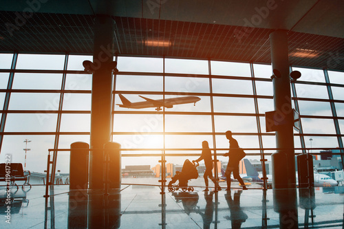 people in airport, silhouette of young family with baby traveling by plane
