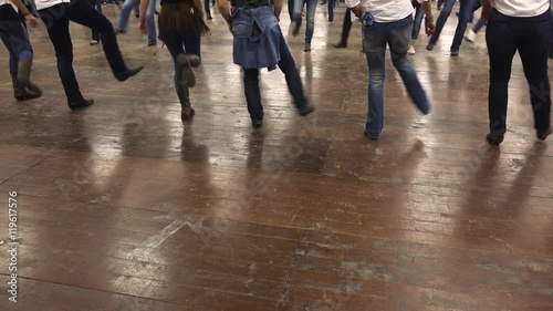Legs of western dancers dancing a choreography at a country festival, wearing cowboy boots, jeans and USA flag. Learning line dance. Music, traditions and fun