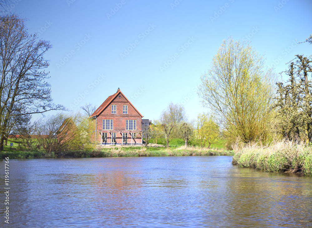 House at a riverside. Farm house in the sun. Sunny day at a river in North Germany. House at a riverside. Farm house in the sun. Sunny day at a river in North Germany.