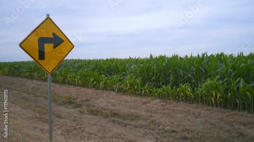 Road sign pointing to wind turbine. Wind turbine on farm field. Directional arrow road sign on rastic road pointing to wind generators. Sustainable energy resource. Wind power generation photo