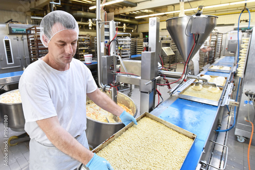 Tableau sur toile Mann stellt Kuchen in einer Großbäckerei am Fliessband her // man presents cakes