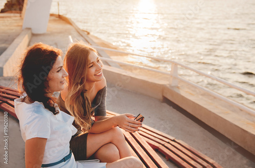 Close-up portrait of happy mother with teenage daughter. Sunset light.